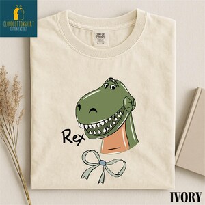 a white t-shirt with a cartoon dinosaur graphic and the name "Rex" printed on it.