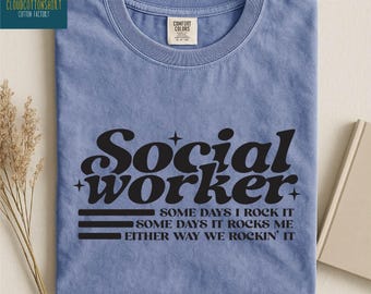 May include: Blue jean t-shirt with the words "Social worker" in a retro font. The shirt also has the text "Some days I rock it, some days it rocks me, either way we rockin' it."