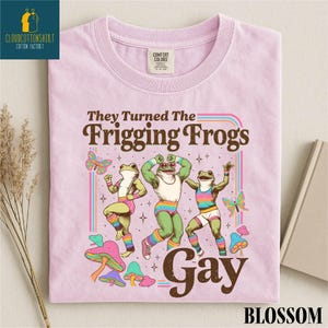 Pu&ograve; includere: T-shirt rosa chiaro con la scritta "They Turned The Frigging Frogs Gay" in marrone. La maglietta presenta un disegno di tre rane in abbigliamento sportivo colorato, con farfalle e funghi. La maglietta ha un'etichetta Comfort Colors.