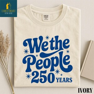 A white t-shirt with a blue and white design that says "We the People 250 years" printed on it.