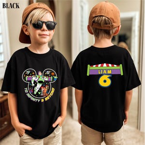 A young boy wearing a black t-shirt with a character from the Toy Story franchise, specifically Buzz Lightyear, and a name tag on the back.