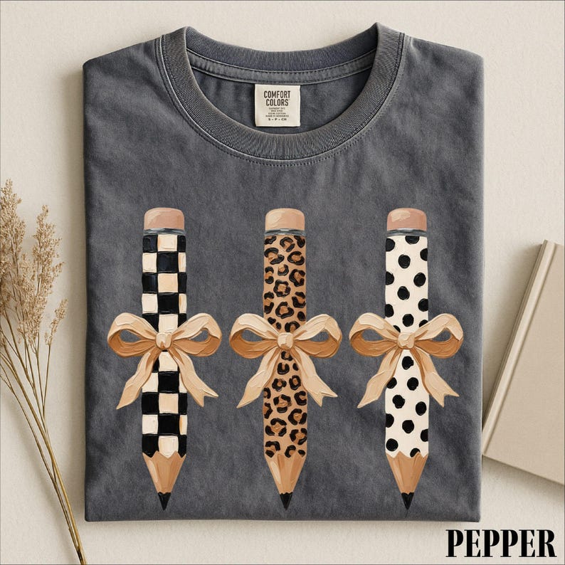 A gray t-shirt with a graphic design of three pencils with bows and leopard print patterns.