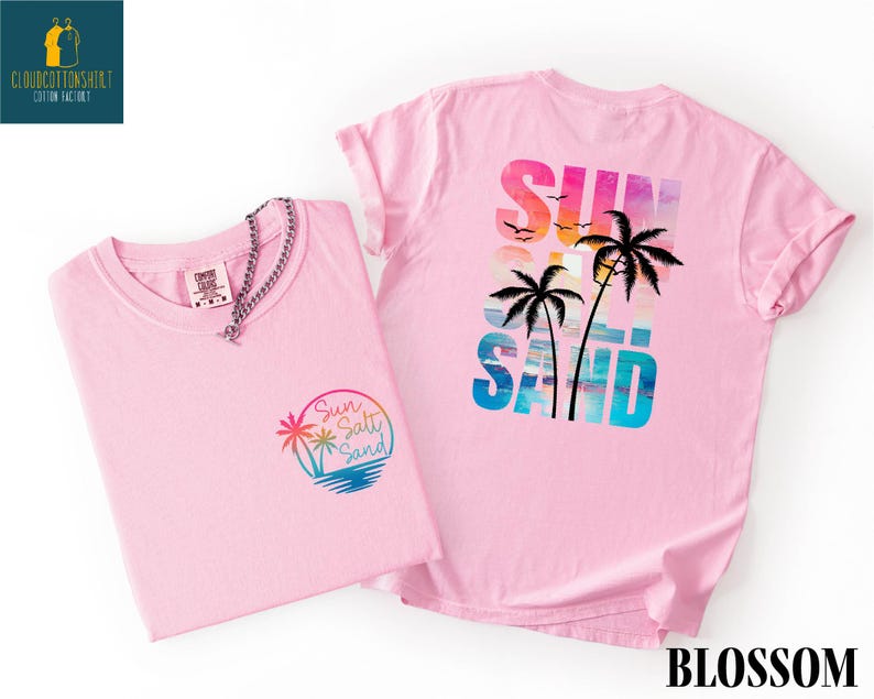 two pink t-shirts with a beach-themed design, including palm trees and a sunset.