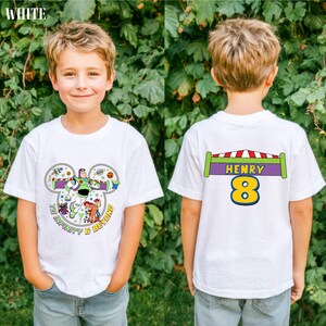 A young boy wearing a white t-shirt with a character from the Toy Story franchise, specifically Buzz Lightyear, and the name "HENRY 8" printed on the back.