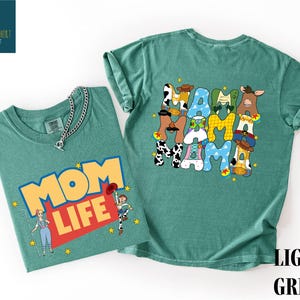 two t-shirts with different designs. The t-shirt on the left has a colorful graphic with a woman and a cow, while the t-shirt on the right has a large graphic with the word "MOM" and various cartoon animal characters.