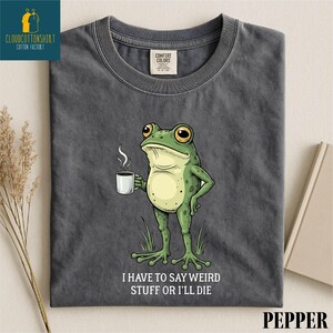 A gray t-shirt with a cartoon frog holding a cup of coffee and the text "I HAVE TO SAY WEIRD STUFF OR I'll die" printed on it.
