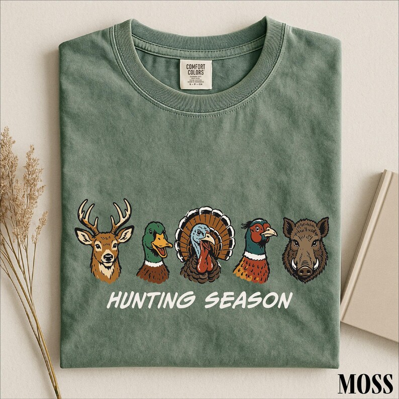 A green t-shirt with a graphic design of various hunting animals, including a deer, turkey, pheasant, and boar, along with the text "HUNTING SEASON".