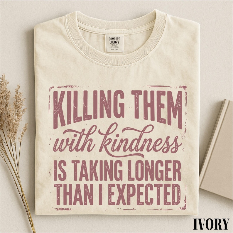 A white t-shirt with a printed message that reads "Killing them with kindness is taking longer than I expected".