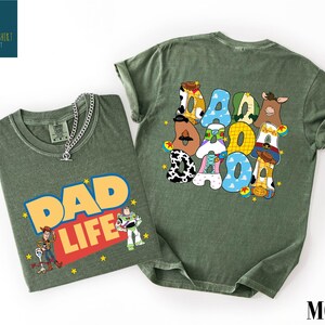 two green t-shirts with cartoon characters and text related to the theme of "DAD LIFE".