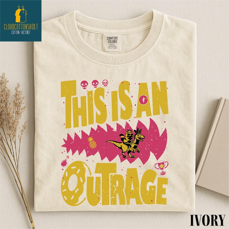 a white t-shirt with a colorful graphic design, including text and illustrations, such as a dinosaur and a trophy.