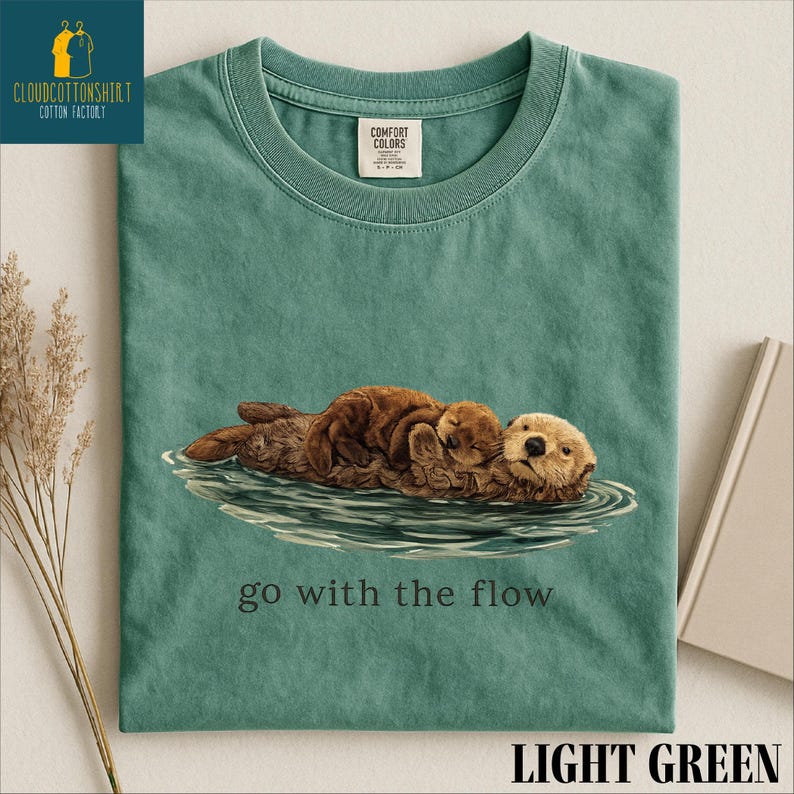 A green t-shirt with an illustration of an otter and the text "go with the flow" printed on it.