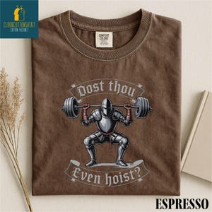 a brown t-shirt with a graphic design depicting a knight lifting a barbell, accompanied by the text "Do you even hoist?"