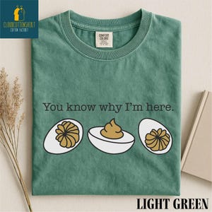 May include: Light green t-shirt with the text "You know why I'm here." and illustrations of deviled eggs. The shirt has a crew neck and a Comfort Colors tag. The words "LIGHT GREEN" are at the bottom.