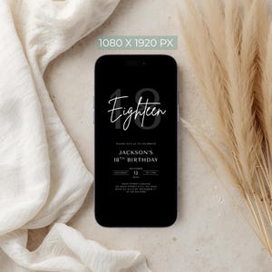 May include: A black smartphone displays a birthday invitation. The invitation reads "Eighteen" in cursive above "Jackson's 18th Birthday" with date and time details. The phone is set against a neutral background with fabric and dried plants.