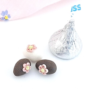 May include: A set of three ceramic mugs with a speckled, matte finish. Each mug features a different color: light blue, cream, and gray. The mugs have a simple, modern design with a rounded shape and a comfortable handle.