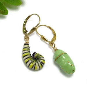 May include: A pair of gold earrings with a green and yellow striped caterpillar and a green chrysalis charm.