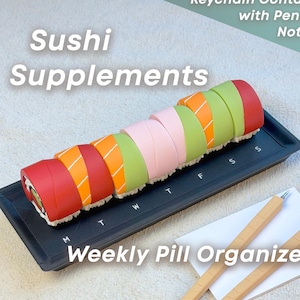 May include: A black weekly pill organiser shaped like sushi rolls, with the text "Sushi Supplements" and "Weekly Pill Organizer." The organiser includes a notepad, pens, and chopsticks. The sushi rolls are red, orange, pink, and green.