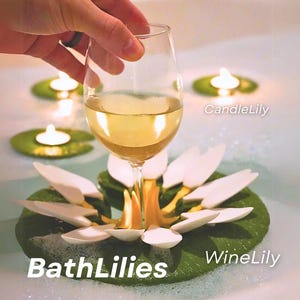 Könnte beinhalten: Ein Weinglas mit Weißwein wird über einem dekorativen Seerosenblatt mit weißen Blütenblättern und einem grünen Blatt gehalten. Das Bild enthält den Text "BathLilies", "WineLily" und "CandleLily". Schwimmkerzen sind im Hintergrund.