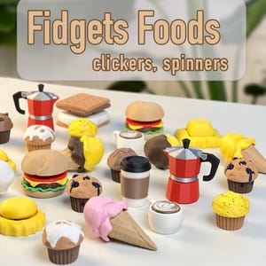 Pode incluir: Uma coleção de brinquedos fidget em miniatura com tema de comida, incluindo uma cafeteira espresso vermelha, cupcakes, um hambúrguer e um cone de sorvete. A imagem tem o texto "Fidgets Foods clickers, spinners" em fonte marrom claro.