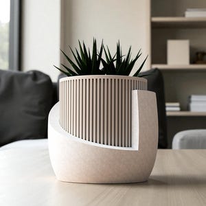 May include: A modern, two-tone planter with a cylindrical, slatted upper section and a curved, solid base. The planter holds a green, spiky plant. The color scheme is neutral, with beige and white tones, suitable for indoor decor.