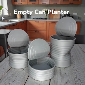 May include: Three grey cylindrical planters designed to resemble open metal cans with lids attached. The planters feature horizontal ridges along the sides and are labeled with the text Empty Can Planter. The set includes three varying sizes.