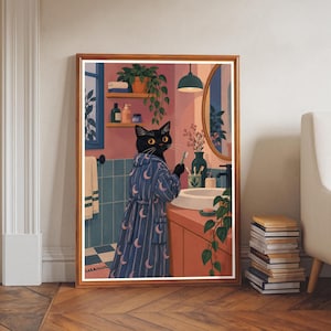 Puede incluir: Una lámina de arte mural enmarcada que muestra a un gato negro con una bata azul con estampado de lunas crecientes, de pie en un baño. El gato sostiene un cepillo de dientes junto a un lavabo blanco, un espejo redondo, estantes y plantas.