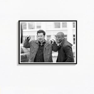 May include: Black and white framed print featuring two men in a street scene. One man gestures with his hands, while the other man has an open mouth. Both men are wearing jackets.