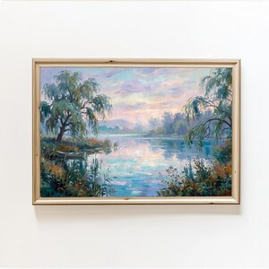 May include: An oil painting in a light wood frame depicting a serene landscape with a calm lake, weeping willow trees, and a small boat near the shore. The sky is filled with soft pastel pink, blue, and purple clouds during a sunrise or sunset.