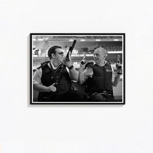 Może przedstawiać: Czarno-biała oprawiona grafika przedstawiająca dwóch mężczyzn w kamizelkach policyjnych, z których każdy trzyma broń palną. Mężczyźni uśmiechają się, być może w sklepie. W tle widoczne są półki z przedmiotami.