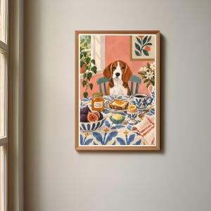 以下が含まれることがあります： 朝食のテーブルに座るビーグル犬を描いた額入りアートプリント。テーブルにはイチジクのボウル、オレンジマーマレードの瓶、トースト、半熟卵、青と白の模様のテーブルクロスが置かれており、部屋の様子が描かれています。