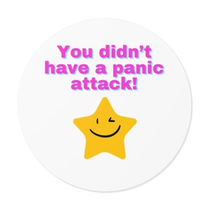 May include: A round white sticker featuring the text "You didn't have a panic attack!" in pink and blue. A yellow star with a winking face is below the text. The sticker is designed to be cheerful.