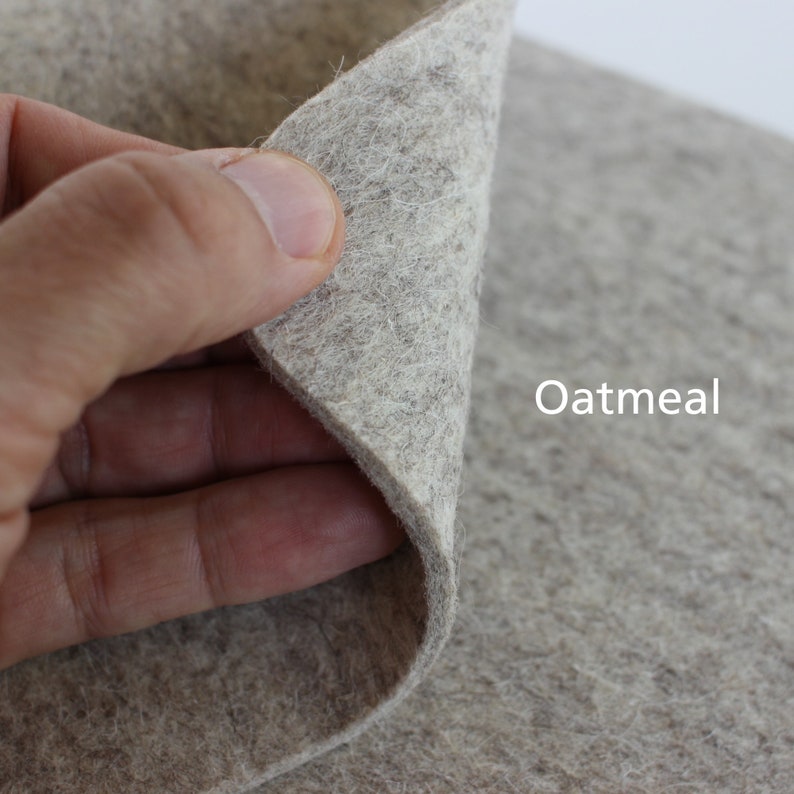 K&ouml;nnte beinhalten: Nahaufnahme eines hellbraunen Filzstoffes. Der Stoff wird in einer Hand gehalten und das Wort "Oatmeal" ist auf den Stoff gedruckt.