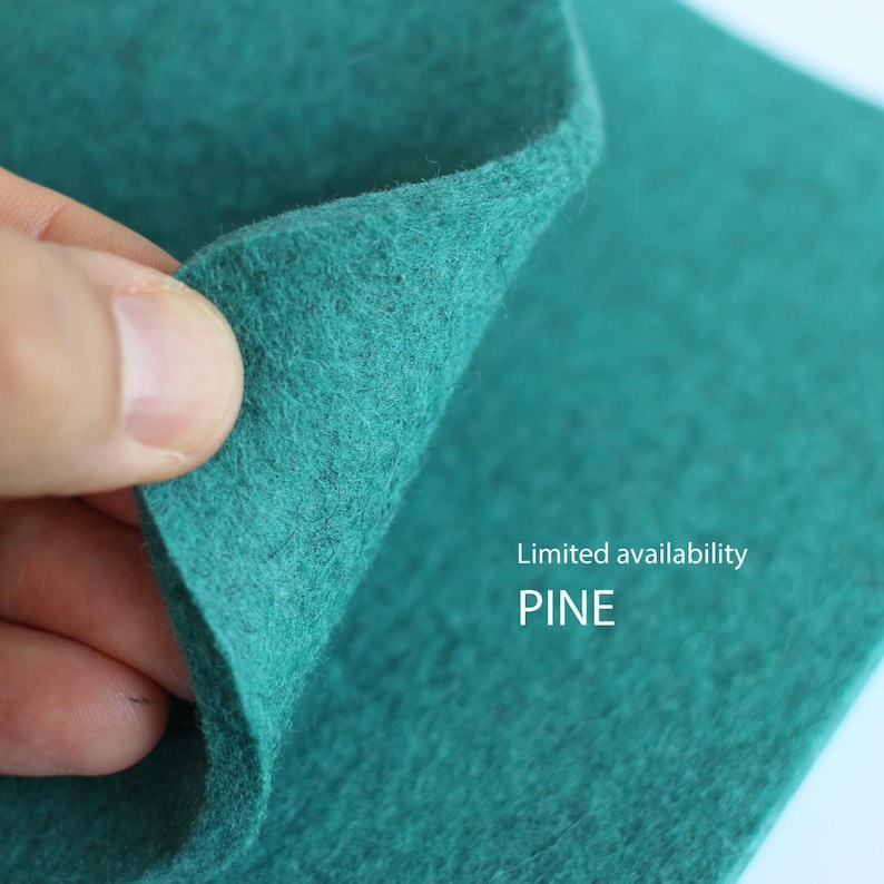 May include: A sheet of dark teal felt fabric with a textured, fibrous surface. The material is folded over to reveal its thickness and density. The text "Limited availability PINE" is printed in white on the lower right side of the fabric.