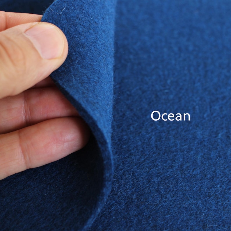 Puede incluir: Primer plano de una tela de fieltro azul oscuro con la palabra "Ocean" impresa en blanco.