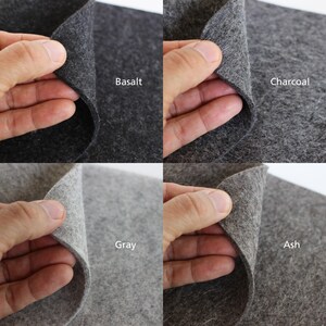 K&ouml;nnte beinhalten: Vier Stoffproben aus Filz in verschiedenen Graut&ouml;nen. Der Filz ist in der Mitte gefaltet und wird von einer Hand gehalten. Die Farben sind Basalt, Anthrazit, Grau und Asche.