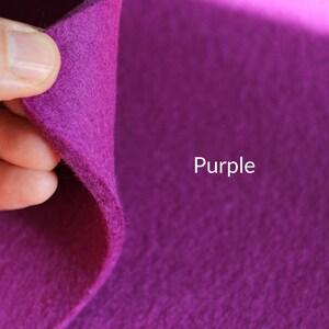 May include: A close-up of a purple felt fabric. The fabric is soft and textured, and the color is a rich, deep purple.