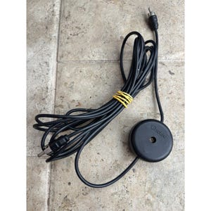 Pode incluir: Cabo preto da marca Chelsea com um componente redondo preto e uma ficha. O cabo é agrupado com uma fita elástica amarela. O componente tem o nome da marca Chelsea impresso.