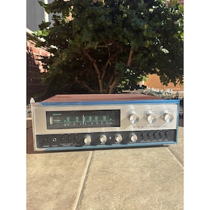 Puede incluir: Receptor Sansui vintage con frontal plateado, ribete azul y parte superior de malla marrón. Cuenta con un dial de sintonización, varias perillas y botones. Diseñado para equipos de audio.