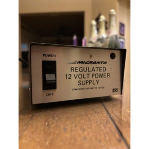 May include: A silver Micronta regulated 12-volt power supply with a black on/off switch. The text on the front reads "REGULATED 12 VOLT POWER SUPPLY" and "CONVERTS 120 VAC TO 12 VDC".