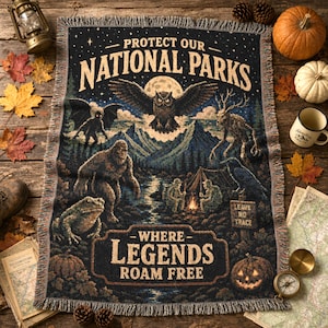 May include: A woven throw blanket featuring a dark forest scene with a large owl, a sasquatch, a deer-like creature, and a campfire. The text reads PROTECT OUR NATIONAL PARKS and WHERE LEGENDS ROAM FREE, with a small sign that says LEAVE NO TRACE.