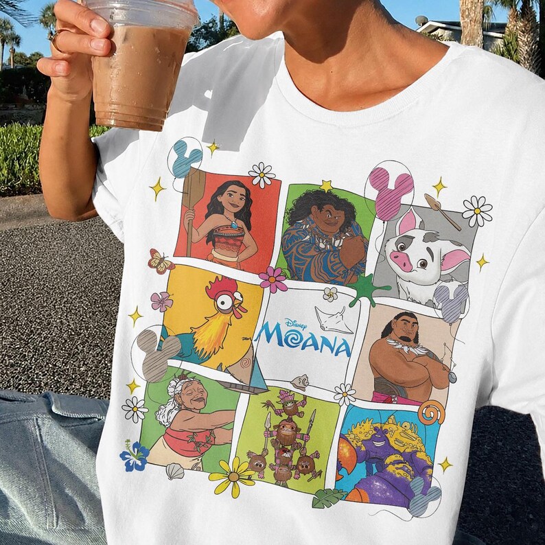 Op de afbeelding: Wit T-shirt met een kleurrijke afbeelding van personages uit de Disney-film Moana. Het ontwerp bevat afbeeldingen van Moana, Maui, Pua, Hei Hei en anderen, met het logo van de film. Het is een casual kledingstuk.