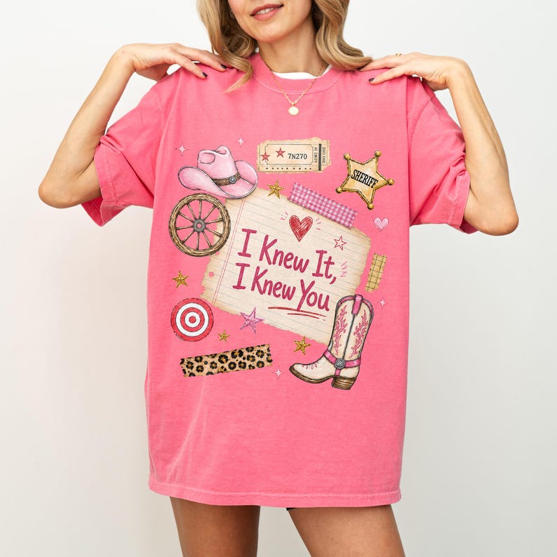 May include: A bright pink t-shirt featuring a graphic print of a cowboy hat, a wagon wheel, a sheriff badge, a cowboy boot, and a lined notepad with the text "I Knew It, I Knew You" surrounded by stars, a heart, and a leopard print strip.
