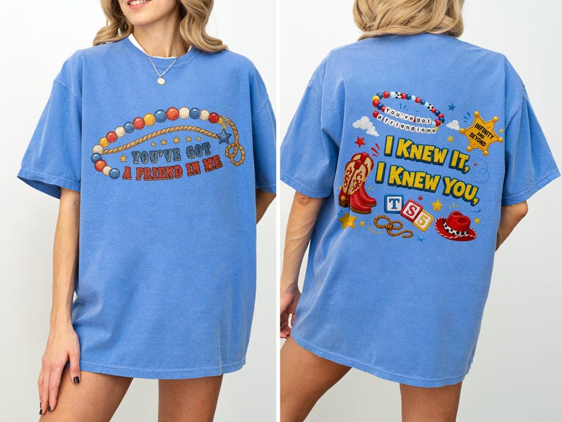 Pu&ograve; includere: Una t-shirt blu a maniche corte con una grafica frontale di una corda di perline e il testo "YOU'VE GOT A FRIEND IN ME." Il retro mostra un braccialetto di perline, una stella da sceriffo, stivali da cowboy, blocchi con "TS5," un cappello e il testo "I KNEW IT, I KNEW YOU."