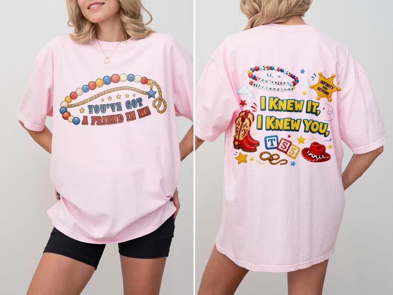 Pu&ograve; includere: Una t-shirt rosa chiaro con una grafica frontale di una collana di perline colorate e il testo "YOU'VE GOT A FRIEND IN ME". La grafica sul retro mostra una collana di perline, una stella da sceriffo con "INFINITY AND BEYOND", uno stivale, un cappello e "I KNEW IT, I KNEW YOU".