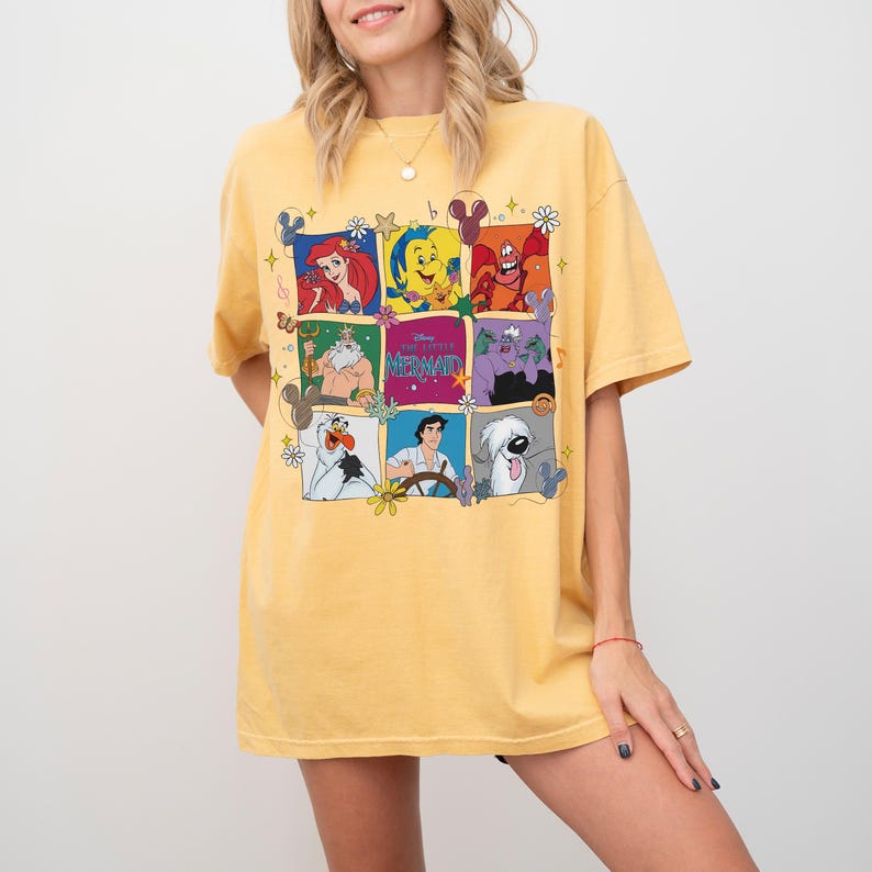 May include: Yellow t-shirt featuring a grid of colorful cartoon character illustrations. The shirt has a crew neck and short sleeves. The graphic includes characters from a popular animated film. The shirt is made of a soft material.