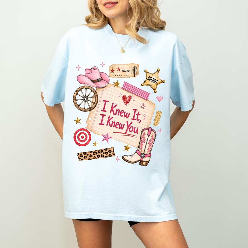 May include: A light blue t-shirt featuring a graphic print of a pink cowboy hat, a wagon wheel, a sheriff badge, a leopard print strip, and a boot. A central notepad graphic displays the text "I Knew It, I Knew You" with a red heart icon.
