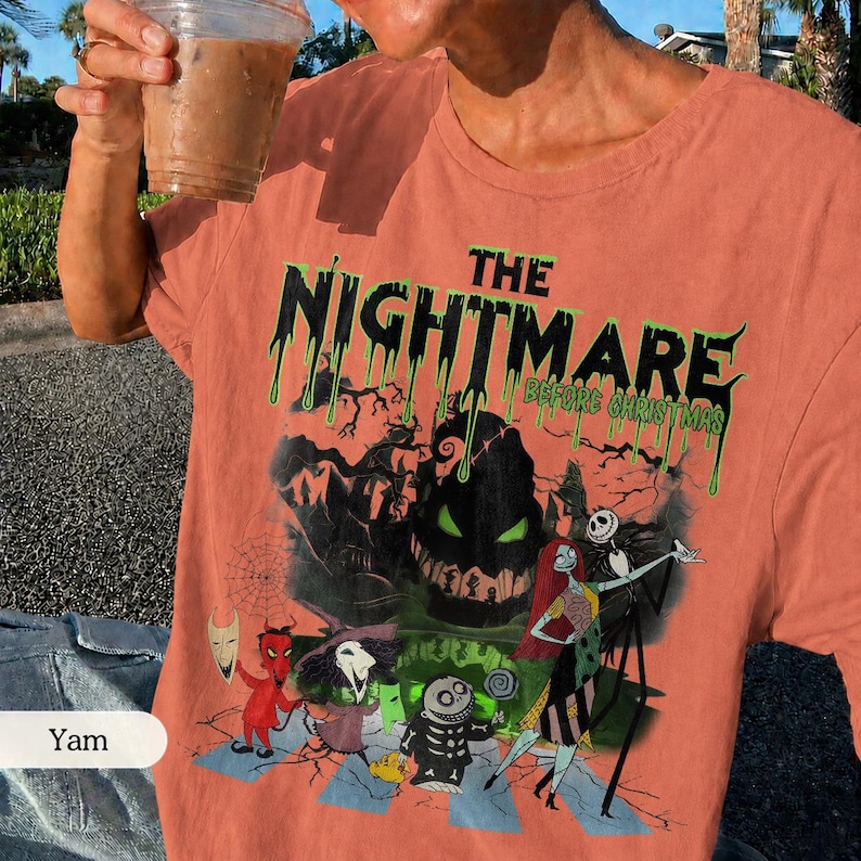 K&ouml;nnte beinhalten: Korallenfarbenes T-Shirt mit einem Grafikdesign aus "The Nightmare Before Christmas". Das Design zeigt den Filmtitel in tropfenden gr&uuml;nen Buchstaben sowie Charaktere wie Jack Skellington und Sally. Das Shirt hat einen klassischen Rundhalsausschnitt.