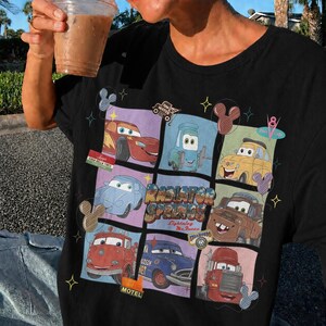 May include: A black t-shirt featuring a grid graphic of various characters from the movie Cars, including Lightning McQueen, Mater, and others. The center text reads Radiator Springs and Lightning McQueen, surrounded by small star and mouse ear icons.