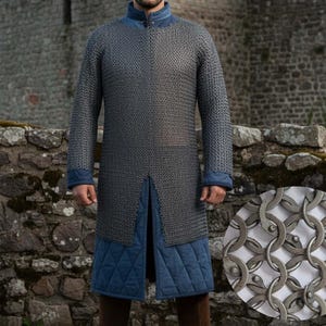 Puede incluir: Una cota de malla plateada con mangas largas, abertura frontal y detalles azules en el cuello y los puños. La camisa se lleva sobre tela acolchada azul. Botas marrones completan el look medieval.