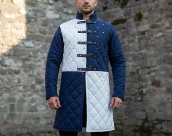 May include: A quilted, long-sleeved coat in navy blue and white. The coat features a diamond pattern, leather straps with buckles, and metal studs. The garment is designed with a stand-up collar and is suitable for historical reenactment or costume.